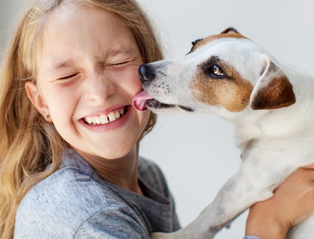 A girl laughs as she plays with her dog.